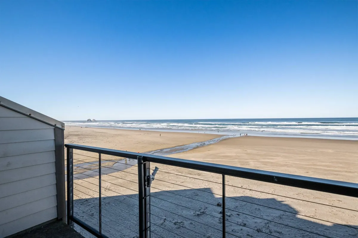 This image presents a sweeping view of the ocean waves rolling onto a sandy beach, with distant rock formations creating a classic Oregon coastal backdrop. The scene exudes an inviting sense of relaxation and adventure, emphasizing the natural beauty that draws visitors to Rockaway Beach.