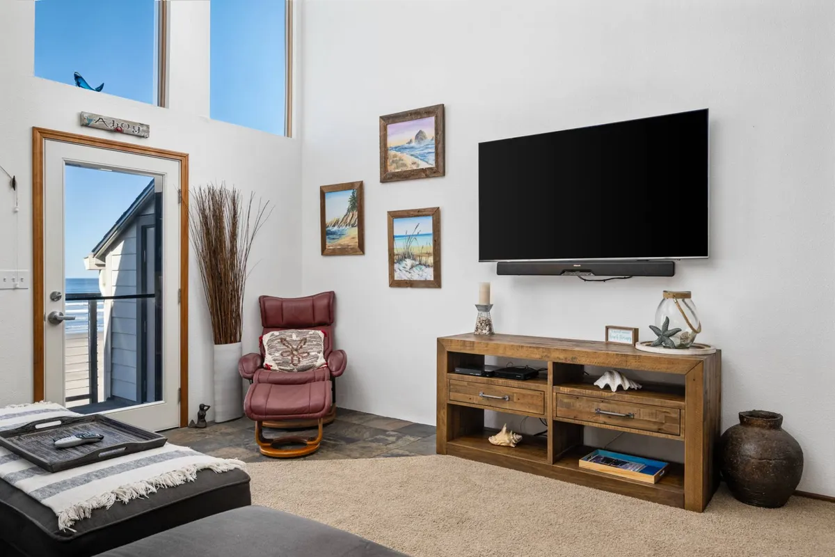 A cozy, well-lit living area featuring a large TV, comfortable chair, and vibrant wall art, with a door leading directly outside. The scene invites group relaxation, movie nights, and storytelling after a day’s adventures.