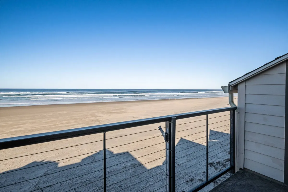 A tranquil stretch of Rockaway Beach at daybreak, with soft sand leading directly to the calm Pacific Ocean. Gentle waves roll to shore under a pastel sky, inviting strolls and moments of reflection. There are no crowds, just wide-open beaches and the soothing sound of the sea.