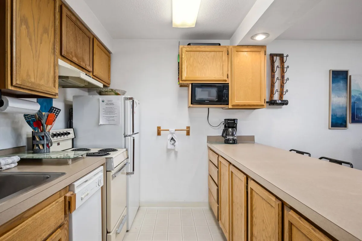 The heart of the kitchen is on display, with a modern counter, stove and oven, refrigerator, microwave, and plenty of room for meal preparation. The space looks casual and welcoming, ideal for both quick breakfasts and more elaborate cooking sessions.